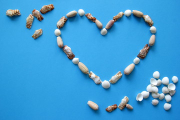 A heart from different seashells on the blue background for Valentine's Day.