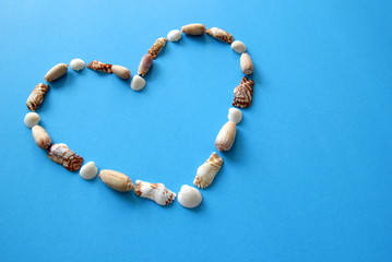 A heart from different seashells on the blue background for Valentine's Day.