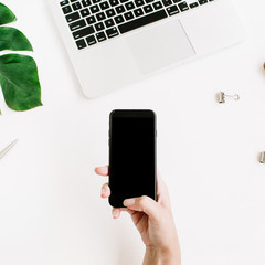 Mockup of smartphone with black screen in female hand. Flat lay, top view workspace