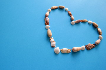 A heart from different seashells on the blue background for Valentine's Day.