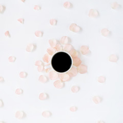 Coffee cup and pink roses petals pattern. Flat lay, top view