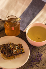 Honeycombs and honey in jar and green tea on wooden background