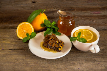 Honeycomb, honey in jar, green tea, lemon with leaf and mint on