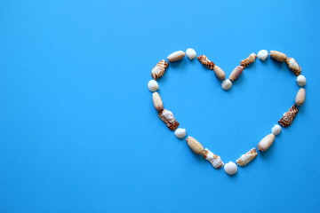 A heart from different seashells on the blue background for Valentine's Day.