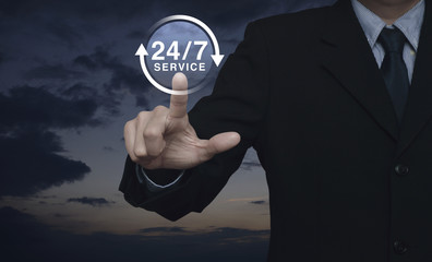 Businessman pressing button 24 hours service icon over sunset sky with clouds, Full time service concept