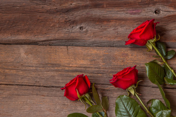 Obraz premium Red roses on wooden background, top view