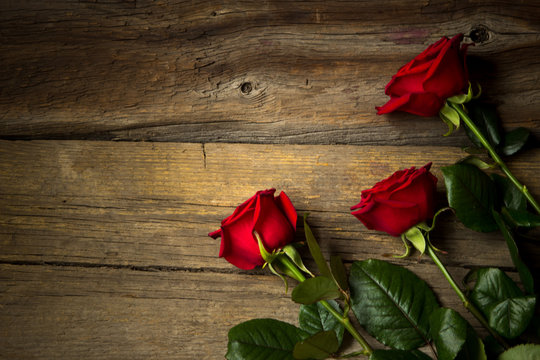 Red roses on wooden background, top view