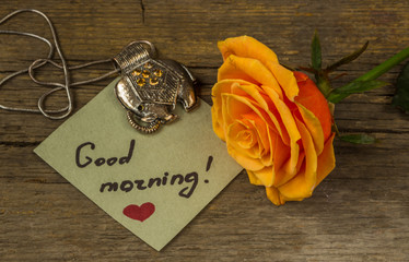 Good morning text on a paper, orange rose flower and decoration