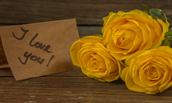 Yellow roses, gift box and card with text I love you