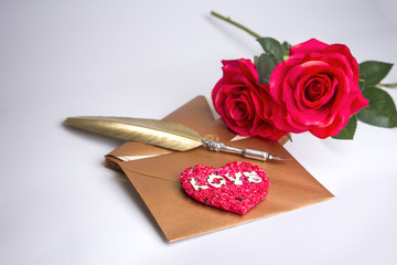 Valentine concept: Love letter with golden writing quill and two red roses