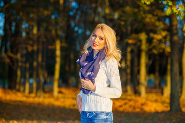 beautiful blonde girl in a white sweater freezing in the park