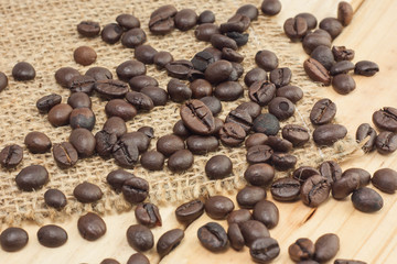 Coffee beans on sackcloth and wood background.