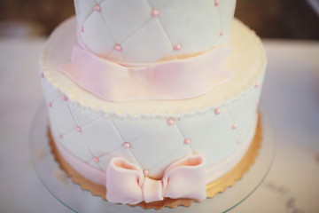 Pink glaze pearls and pink bow on delicious white cake