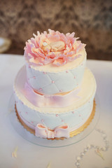 Tasty tired cake with pink flower and figure of child on top