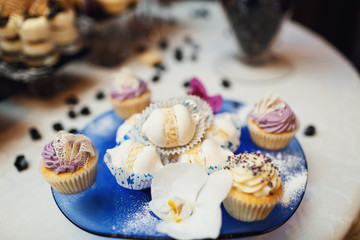 Blue glass tray with delicious white macaroons and cupcakes