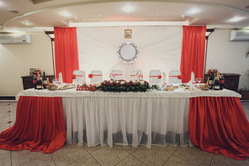White dinner table covered with red cloth and red roses
