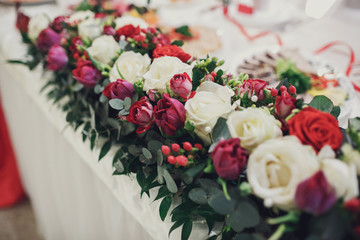 Garland of white and red roses lies on white dinner table for ne