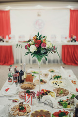 Thin vase with little bouquet of roses stands on white table pre