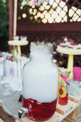 Glass barrel with punch and smoke over it stands on table