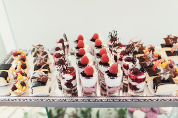 Cold desserts with cream and berries stands on glass table