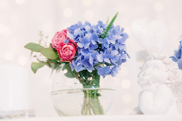Look from below at little vase with blue hydrangea and tiny pink