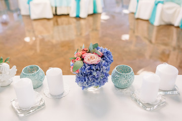 Little bouquet of blue hydrangeas and roses stands  between whit