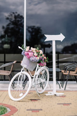 Fototapeta na wymiar Decorative white bicycle and arrow stand in the middle of restau