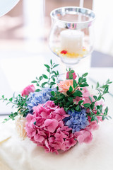 Little bouquet of hydrangeas and greenery stands before glass wi