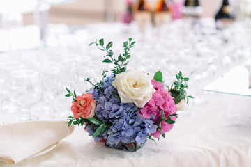 Little bouquet of hydrangeas and roses stands on table with empt