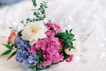 Little bouquet of hydrangeas and roses stands on table with empt