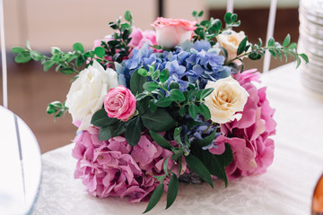 Beautiful bouquet of beige roses and pink hydrangeas on white ta