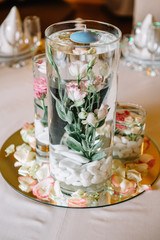 Glass vases with roses in water and little candles on top stand