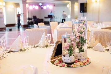 Roses in water stand on mirror tray in the centre of dinner tabl