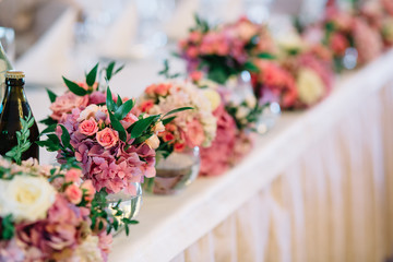Little bowls with bouquets of hydrangeas and roses stand in the