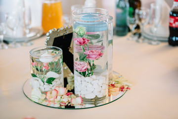 Mirror tray with rose petals and vases with candles stands in th