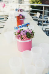 Pink round box with violet flowers stands on white dinner table
