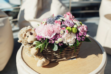 Toy monkey hugs bascket with beautiful  pink flowers