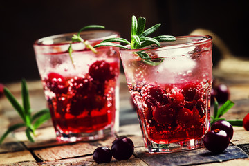 Cranberry beverage with ice and berries, vintage wooden backgrou