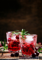 Cranberry beverage with ice and berries, vintage wooden backgrou