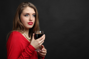 Sexy girl posing with a glass of wine in her hand on a dark background.