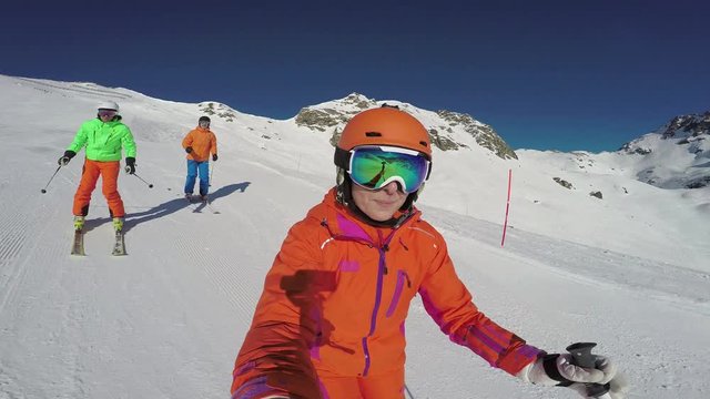 4k skiing footage, selfie point of view with action cam of three good skiers skiing down ski slope on sunny winter day
