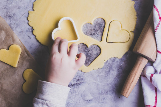Baking love heart cookies for Valentine day. Top view. Children's hands to help prepare sweet cookies