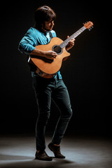 Cool guy standing with guitar on dark background
