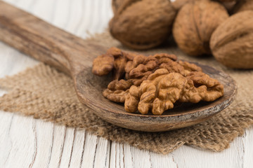 Walnuts in a wooden spoon and an old white wooden table.