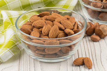 Almonds in a glass bowl on the old wooden table.