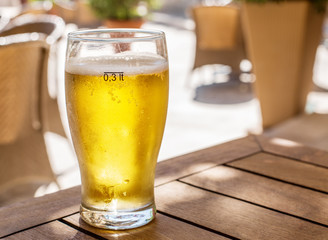 Glass of light beer on the wooden table.