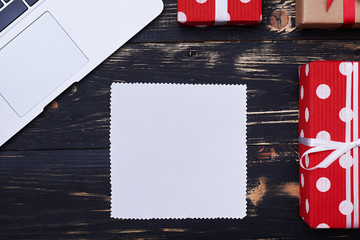 Blank greeting card surrounded by gift boxes and silver laptop