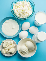 Protein products: cheese, cream, milk, eggs on the blue backgrou