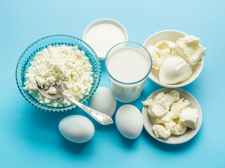 Protein products: cheese, cream, milk, eggs on the blue backgrou