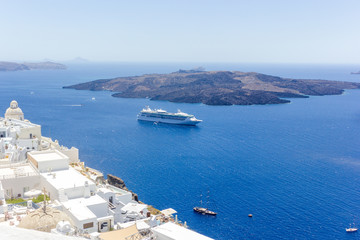 Beautiful panoramic view on the mediterranean sea, caldera and volcano. Traditional white architecture of Santorini island, Thira, Greece. Cruise ship in blue sea.